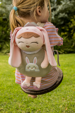 Child wearing a plush backpack with a bunny backapck on a grassy area