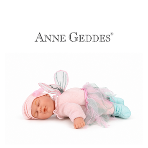 A realistic baby doll wearing a pink fairy costume with a pink hat, pink tulle skirt, and light blue leggings, lying on a white background with the Anne Geddes brand name above.