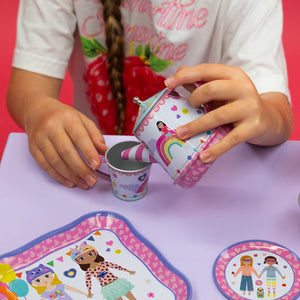 Child playing with a toy tea set on a pink surface