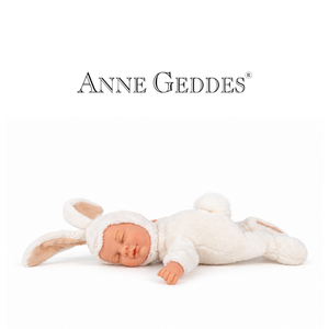 A realistic sleeping doll dressed in a white bunny costume with long ears, lying on a white background. The brand name 'ANNE GEDDES' is printed above the doll.