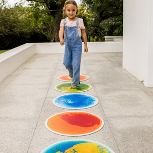 Child walking on colorful circular tiles outdoors