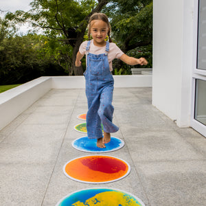 Child jumping on colorful circular tiles on a patio