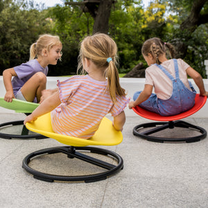 Three children sitting on colorful chairs outdoors 